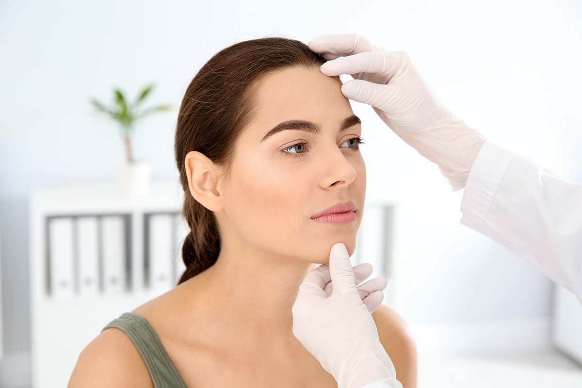 Dermatologist examining patient's face in clinic