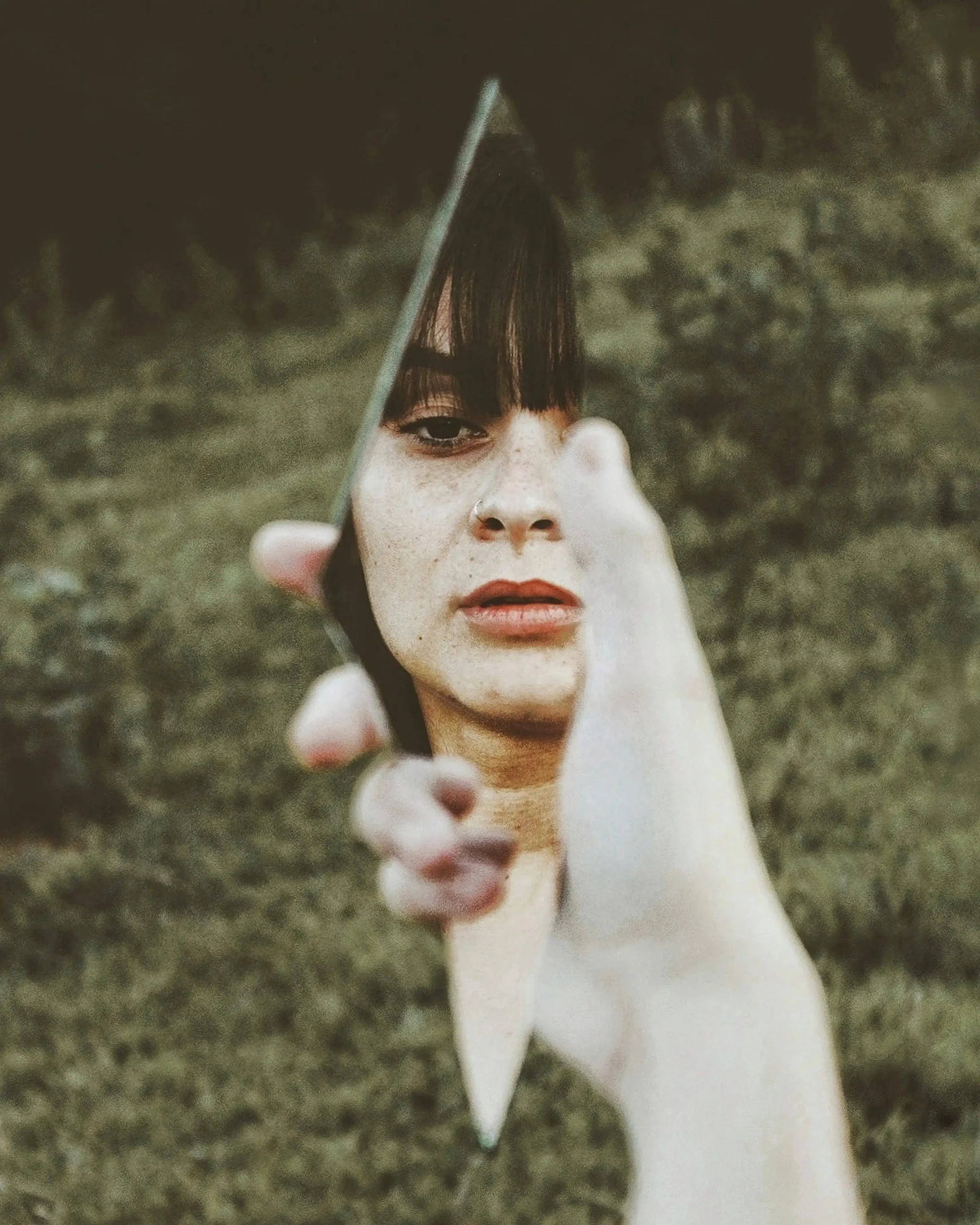 woman looking at herself in a shard of a mirror woman looking at herself in a shard of a mirror